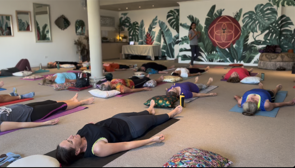 People lying down and relaxing on yoga mats in a yoga room
